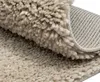 A close-up view of a beige, shaggy rug, showing its texture and the underside. Náhľad obrázku produktu