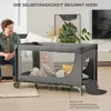 A father watches his baby play in a travel crib in a living room. Podgląd zdjęcia produktu