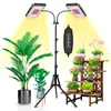 A dual-head LED plant grow light with a tripod stand, illuminating several potted plants on a wooden shelf and on the floor. Anteprima dell’immagine prodotto