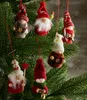 A close-up shot of several knitted Christmas ornaments hanging on a Christmas tree. Podgląd zdjęcia produktu