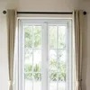 A close-up view of a double door with white frames and glass panes, covered by beige curtains on a black curtain rod. Produktbild-Vorschau