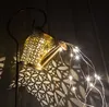 A decorative watering can with LED lights, casting patterned shadows on a wooden surface. Produktbild-Vorschau
