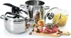 A collection of stainless steel cookware, including a pressure cooker, a large pot, and a frying basket with pasta, along with raw ingredients like meat, garlic, and onion, arranged on a white background. Produktbild-Vorschau