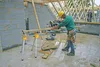 A construction site with a worker using a miter saw. Náhled obrázku produktu