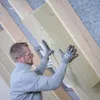A person is installing insulation material in an attic. Produktbild-Vorschau