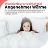 A woman is smiling and peeking out from under a white duvet in a bed. Produktbild-Vorschau