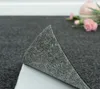 A close-up view of a self-adhesive carpet tile being peeled back, revealing its adhesive backing. Produktbild-Vorschau