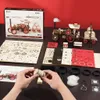 A collection of wooden model building kits and components, including a steam engine model, unassembled parts, and instructions, laid out on a dark surface with a red background. Voir les images du produit