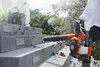 A person is using a leaf blower to clear leaves from a set of outdoor stairs. Produktbild-Vorschau