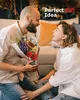 A couple is sitting on the floor, with the man presenting a bouquet of flowers to the woman. Produktbild-Vorschau