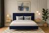 A bedroom scene featuring a navy blue upholstered bed with pillows and a nightstand. Voir les images du produit