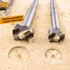 Close-up of two Forstner drill bits with wood shavings and two drilled holes in a wooden surface. Produktbild-Vorschau