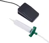 A black foot pedal and a clear syringe with a green nozzle are shown against a white background. Náhled obrázku produktu