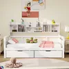 A white wooden daybed with drawers and a bookshelf headboard, decorated with pillows and a stuffed toy. Voir les images du produit