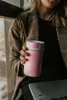 A person holding a pink thermos flask next to a laptop. Náhled obrázku produktu
