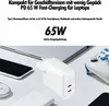 A white USB-C charger is shown on a table with a laptop, smartphone, mouse, and game controller. Produktbild-Vorschau
