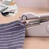 A close-up of a white handheld sewing machine being used on a striped fabric. Náhled obrázku produktu