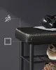 Close-up of a black shoe bench with detailed stitching, showing headphones on top. Produktbild-Vorschau