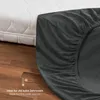 A close-up of a dark gray fitted sheet is shown next to a white mattress. The sheet is partially covering the mattress, and the wooden floor is visible below. Anteprima dell’immagine prodotto