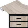 A roll of wood-grain contact paper is shown partially unrolled over the top of a dresser with two drawers. Produktbild-Vorschau