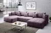 A modern living room with a large purple sectional sofa, a white coffee table, and a framed abstract artwork on a brick wall. Náhľad obrázku produktu