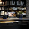 A desk setup with a laptop, two speakers, and bookshelves in the background. Náhľad obrázku produktu