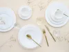 A top-down view of a white dinnerware set arranged on a light beige background with dried floral sprigs. Náhľad obrázku produktu