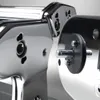 A close-up view of a chrome-plated pasta maker attachment with a black circular component and metal pins. Podgląd zdjęcia produktu
