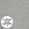 A close-up of grey fabric with a circular logo containing text and a bamboo illustration. Produktbild-Vorschau