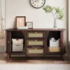 A dark wood sideboard with rattan drawer fronts, decorated with framed art and a plant. Produktbild-Vorschau