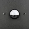 A close-up of a motion sensor on a textured dark gray surface. Voir les images du produit