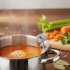 A thermometer is clipped to a pot of simmering soup, with chopped vegetables in the background. Voir les images du produit