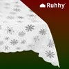 A close-up of a white tablecloth with silver snowflakes and dots, draped over a surface. The background is a gradient of dark red to dark green. Podgląd zdjęcia produktu