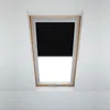 A black blackout roller blind is installed in a wooden framed attic window. Produktbild-Vorschau
