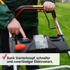 A person's hand is pressing the starter button on a lawnmower. Produktbild-Vorschau