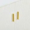 A close-up view of two gold handles on a white ribbed cabinet door. Produktbild-Vorschau