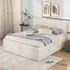 A bedroom scene featuring a bed with storage drawers, pillows, and a blanket, along with decorative elements like artwork and a plant. Náhľad obrázku produktu