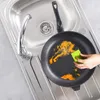 A hand is cleaning a dirty frying pan in a kitchen sink. Anteprima dell’immagine prodotto