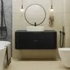 A modern bathroom with a black vanity, white sink, round mirror, and a toilet. Náhled obrázku produktu