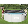 A man and a woman are covering a round swimming pool with a black cover. Podgląd zdjęcia produktu