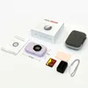 A digital camera and its accessories are laid out on a white surface, with the product box and instruction manual visible. Produktbild-Vorschau