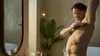 A man is shaving his underarm in a bathroom. Produktbild-Vorschau
