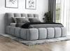 A modern upholstered bed with a headboard and footboard, set up in a bedroom with a rug underneath and artwork on the wall. Produktbild-Vorschau