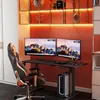 A gaming or computer setup in a room with orange walls and shelves. Náhled obrázku produktu