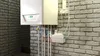 A white boiler unit is mounted on a brick wall, with pipes and electrical connections visible. Anteprima dell’immagine prodotto