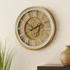 A gold wall clock with Roman numerals and visible gears is mounted on a light-colored wall. A plant is visible in the lower left corner, and a brown vase is on a shelf in the lower right corner. Anteprima dell’immagine prodotto