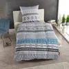 A bed with blue and gray snowflake patterned bedding and a pillow.