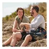 A couple sitting on rocks outdoors, with a backpack and a flask. Podgląd zdjęcia produktu
