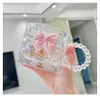 A hand holding a clear glass mug with a pink bow decoration and a beaded handle. Anteprima dell’immagine prodotto