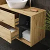 A close-up view of a modern bathroom vanity with drawers and an open shelf, featuring a sink and towels. Produktbild-Vorschau